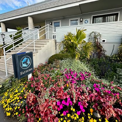 A colorful flowerbed next to a stairway with a sign that says Fathoms