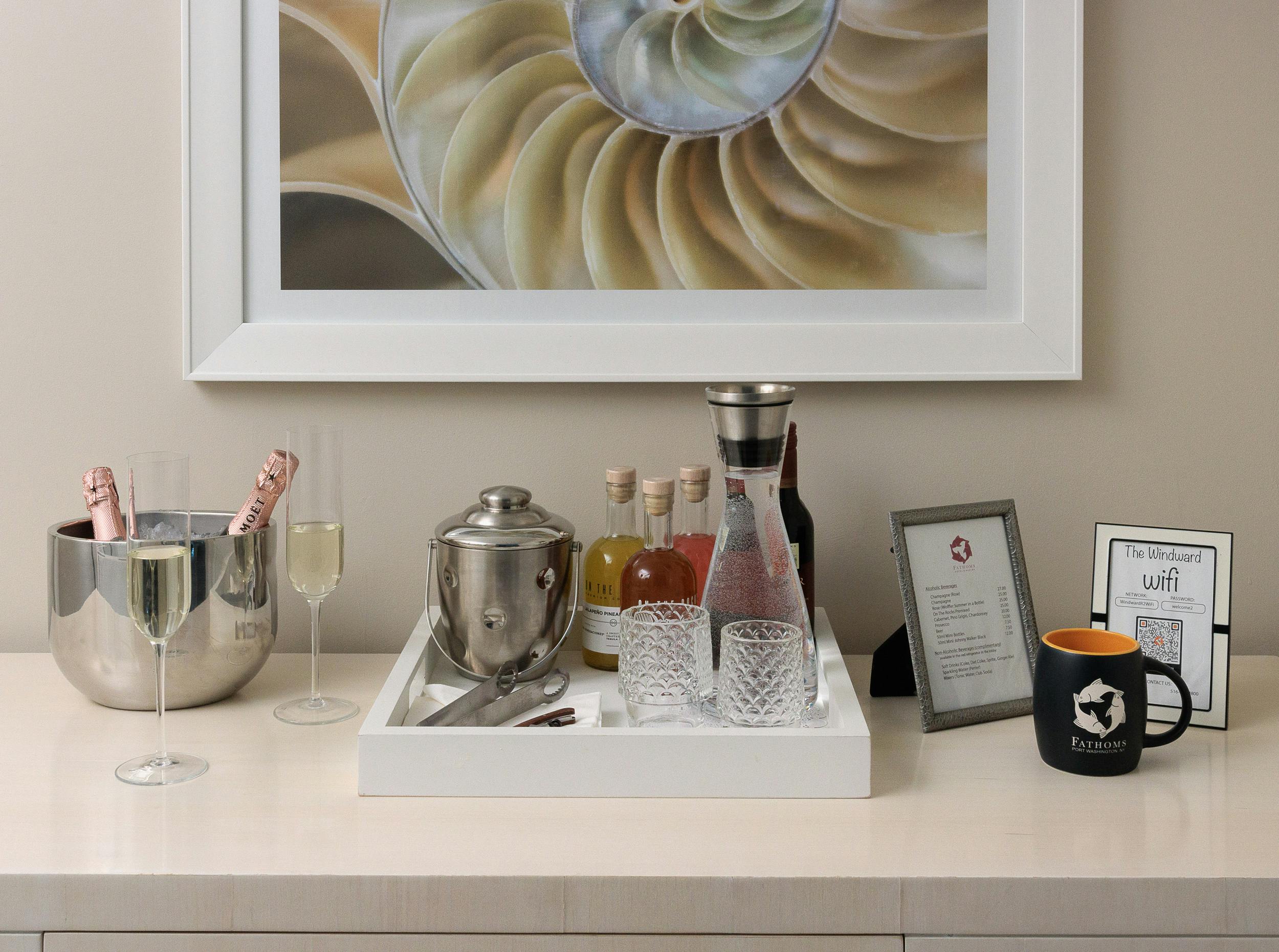 A tabletop setup with champagne, ice bucket, water carafe, mugs and information placards