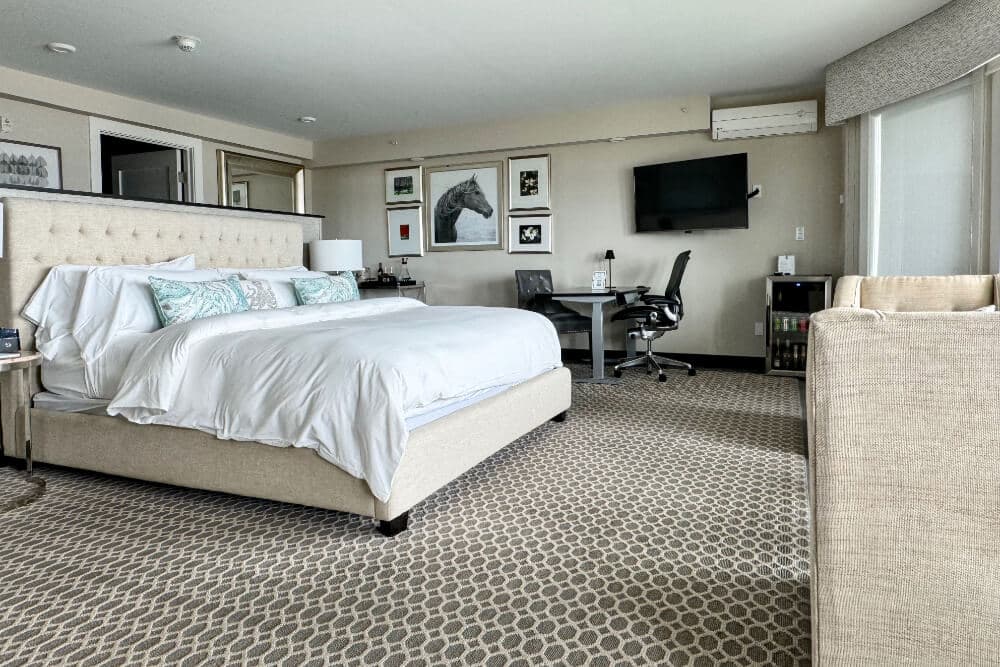 A bedroom with a bed, an office area with table and chairs, and a flat screen TV.