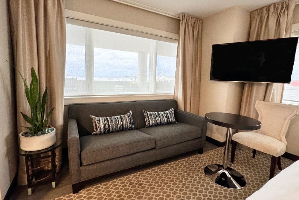 A bedroom with a dresser with chrome framed mirror above it, and a closet with mirrored doors.