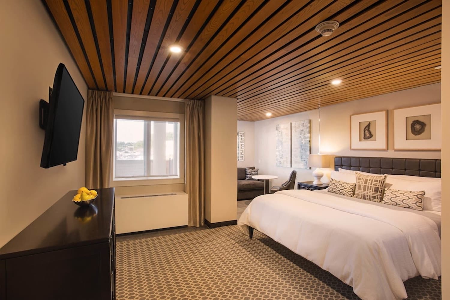 A spacious bedroom with a king bed, a separate sitting area, and dresser.