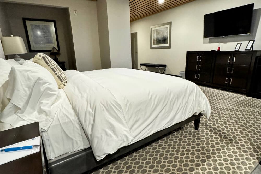 A bedroom with a bed, dresser, and flat screen TV