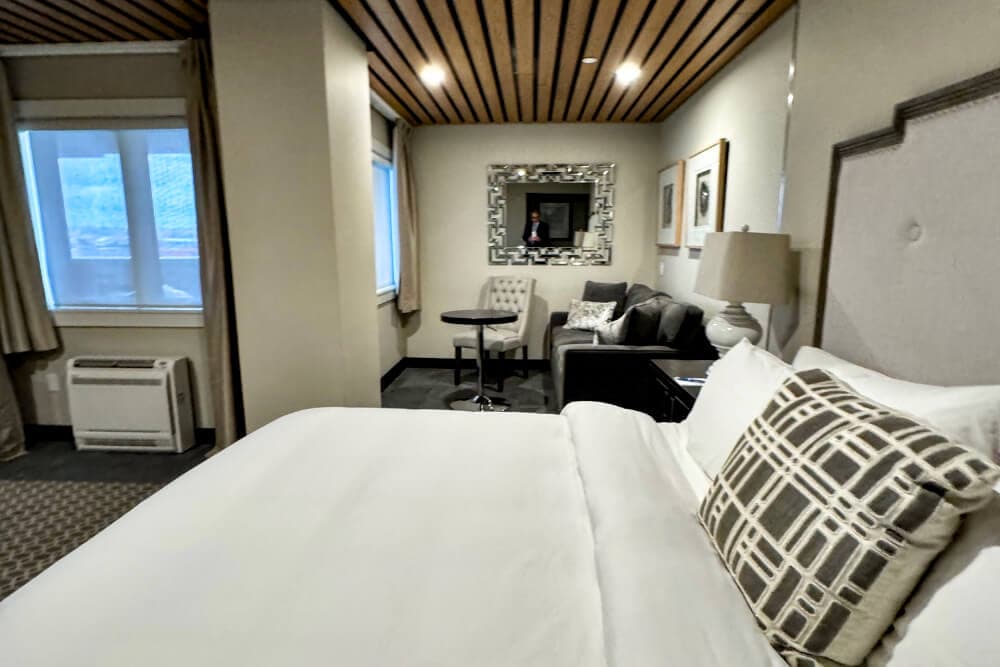 A bedroom with a bed and sitting area with sofa, table and chair.