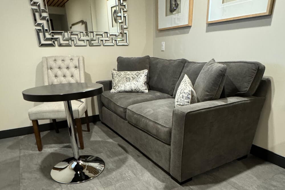 A sitting area with a sofa, small round table, and chair.